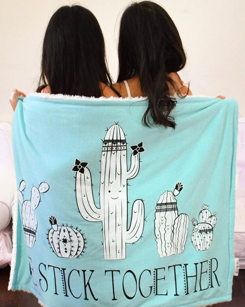 Twin girls posing with their Lil Be "We stick together" Cozy Baby Blanket