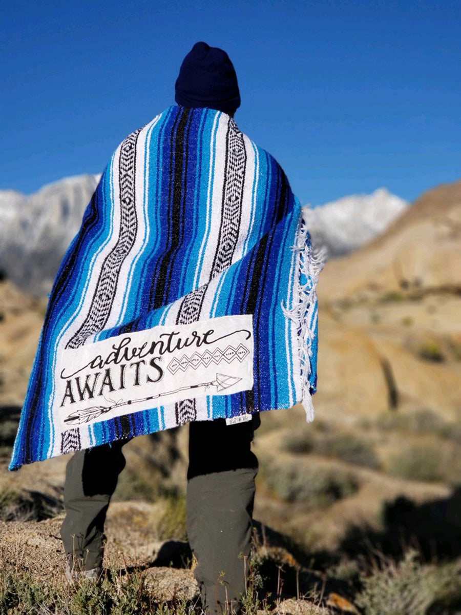 Hiker wrapped with "Adventure Awaits" Blue Throw Blanket