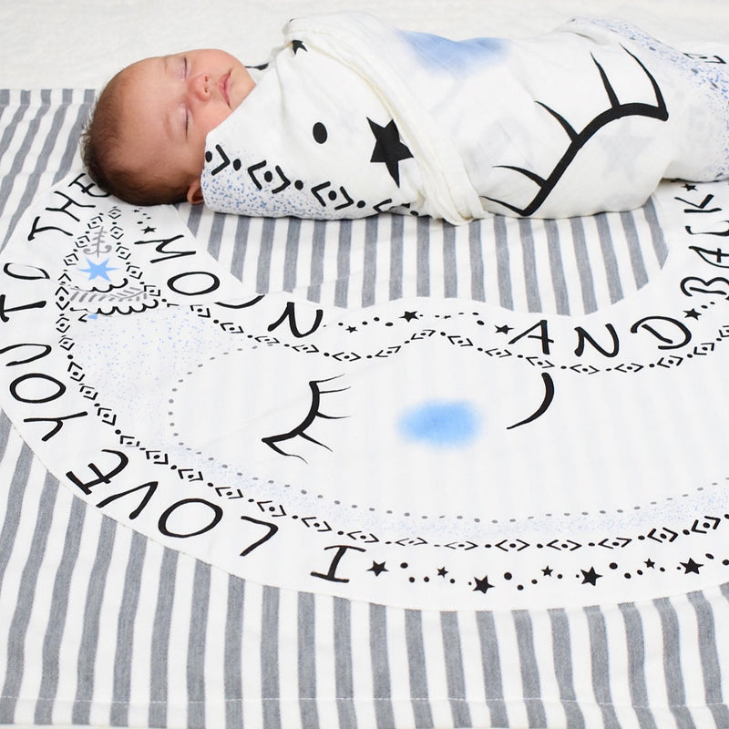 Newborn wrapped in Lil Be Swaddle on I love you to the moon and back baby blanket