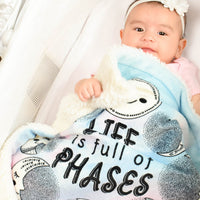 Baby girl laying down with her Life is full of Phases security mini blanket