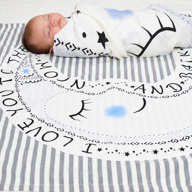 Newborn wrapped in Lil Be muslin swaddle blanket on Magic the Moon Character Shaped Baby Blanket